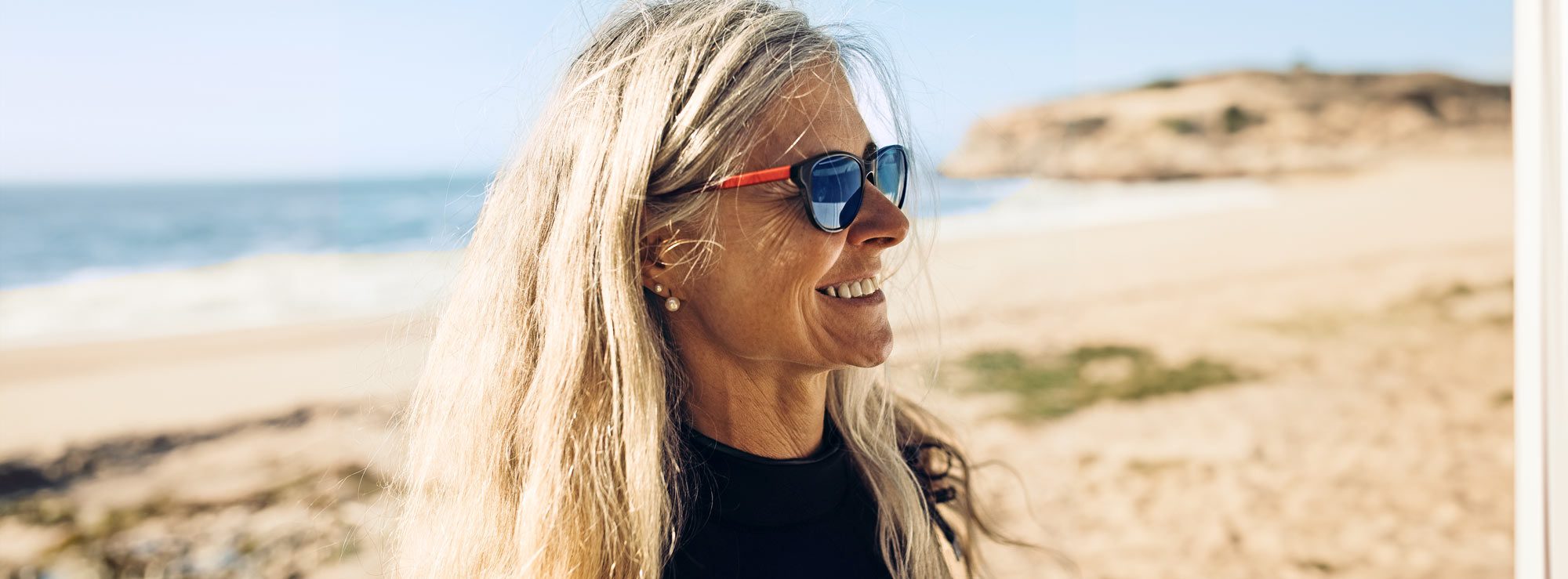 A smiling woman enjoying a warm, sunny day on the SoCal coast